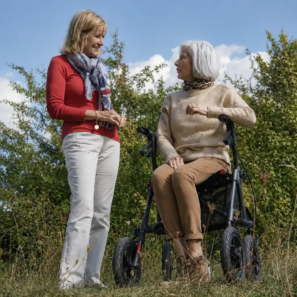 Elderly woman resting on an all-terrain rollator walker outdoors